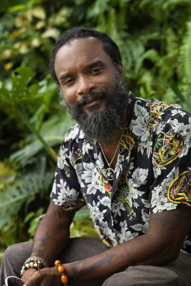 Kerry Mark Green seated outdoors among tropical foliage