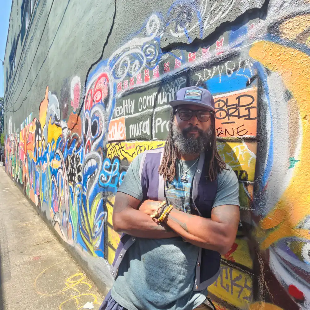 Kerry Mark Green standing before a colorful mural