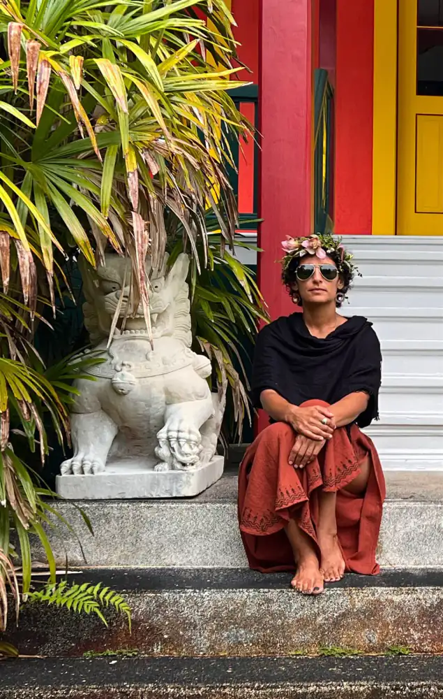 Melody Khodabandeh seated outside a colorful red and yellow building in Hawaiʻi
